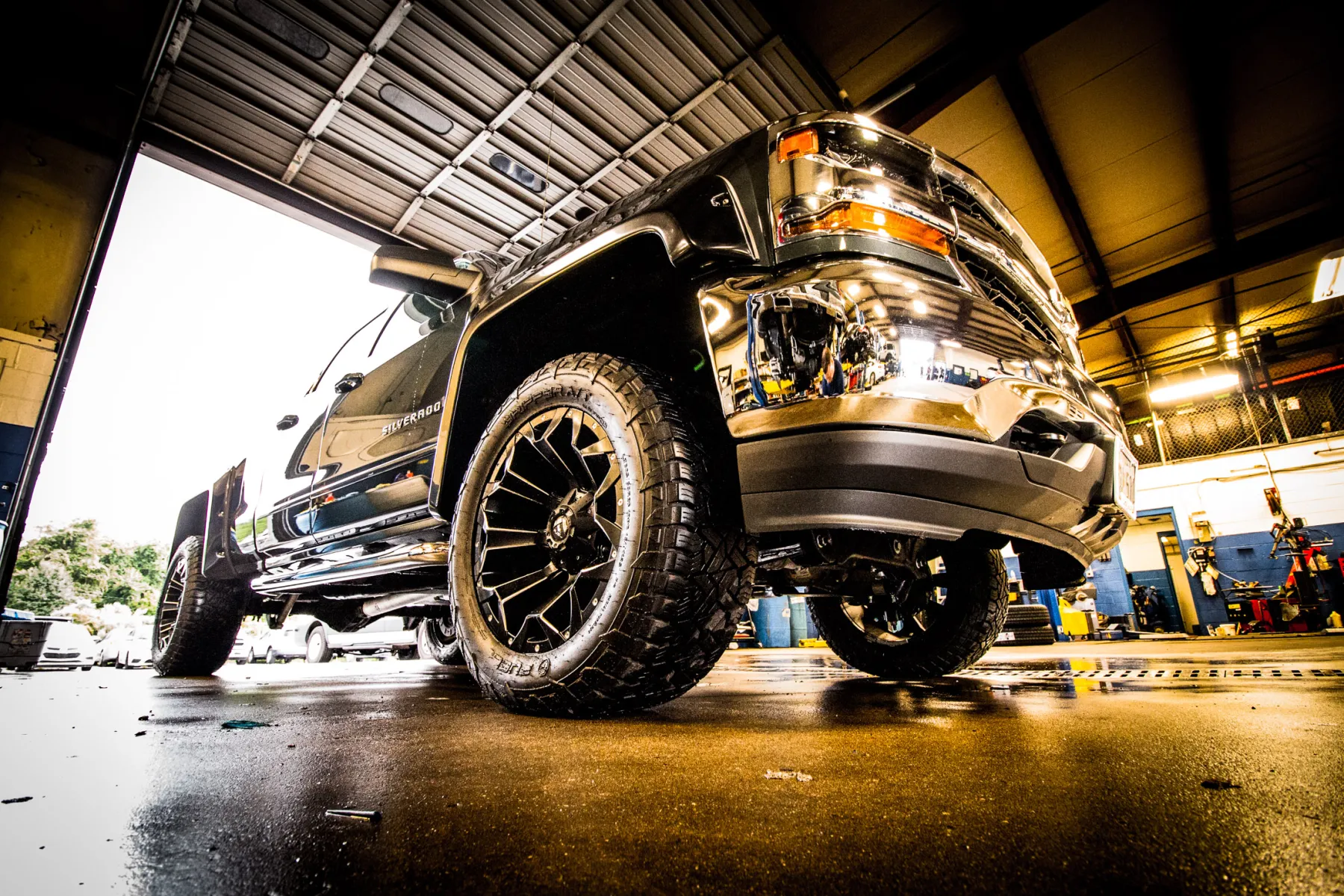 A lifted Silverado up on the alignment rack inside the Apple Off Road shop.